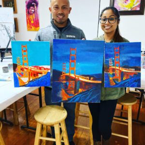 A man and a woman holding paintings