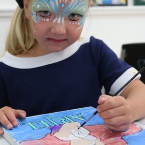 A picture of the young girl painting on the paper