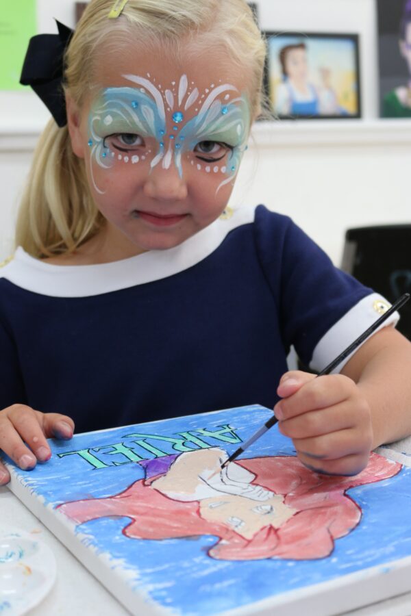 A picture of the young girl painting on the paper