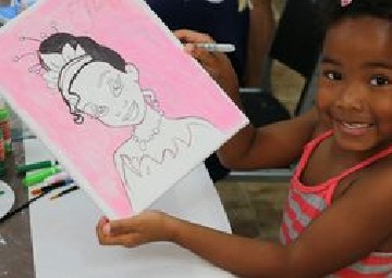 A child smiling at the camera and showing a sketch of a princess