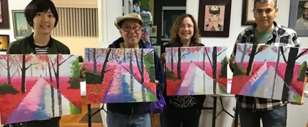 A family at the private art lesson class holding their painting frames