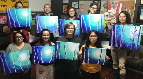 A picture of the people holding their painting frames at the class